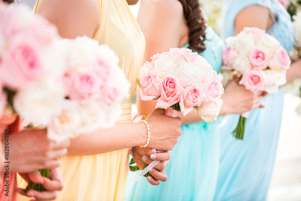 Naklejka premium Bridesmaid holding a bouquet of roses at the wedding.