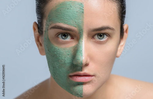 Young woman applaying green face mask - studio portrait photo