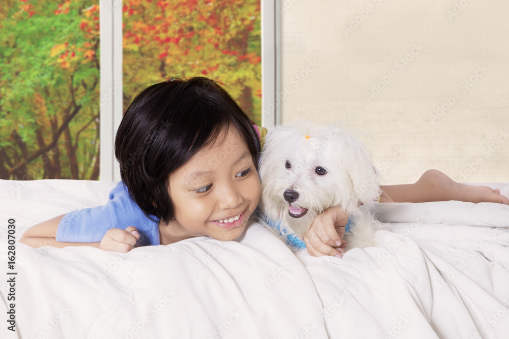 Little girl hugging canine in the bedroom Little girl hugging canine in the bedroom