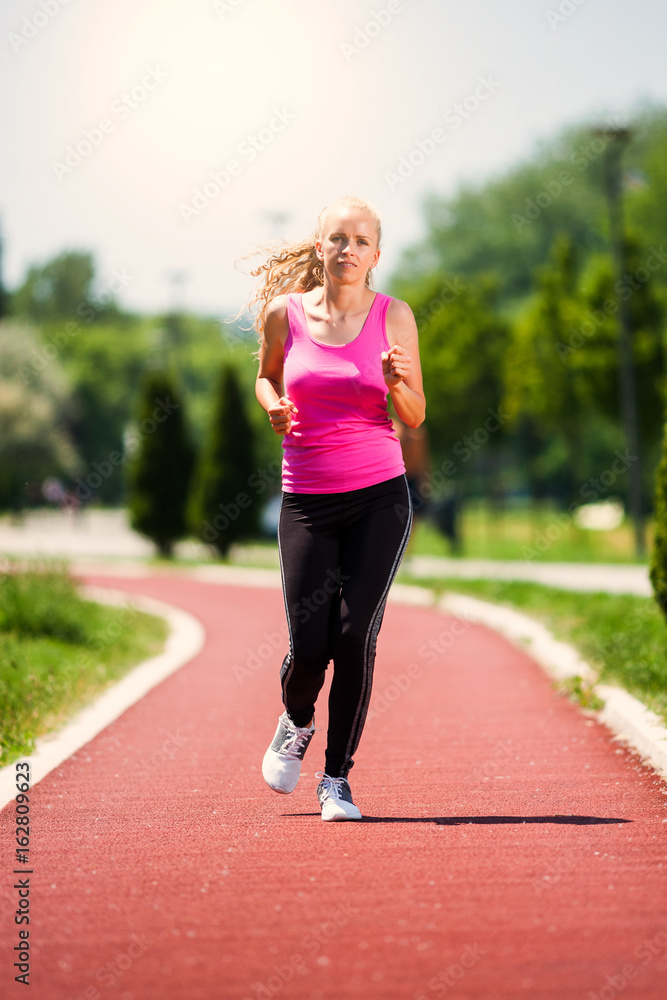 Young woman is jogging on sunny day. 