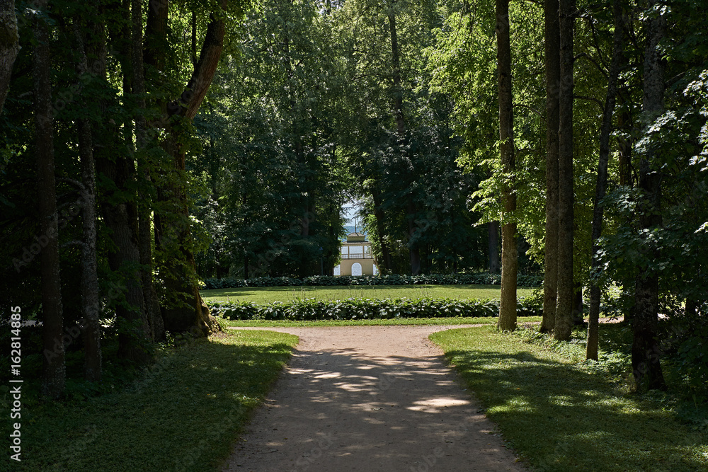 Shady alley in the park/On the sides of the alley are trees that make a shadow. At the end of the alley you can see a two-story house. Russia, Pskov region, nature, landscape Shady alley in the park/On the sides of the alley are trees that make a shadow. At the end of the alley you can see a two-story house. Russia, Pskov region, nature, landscape