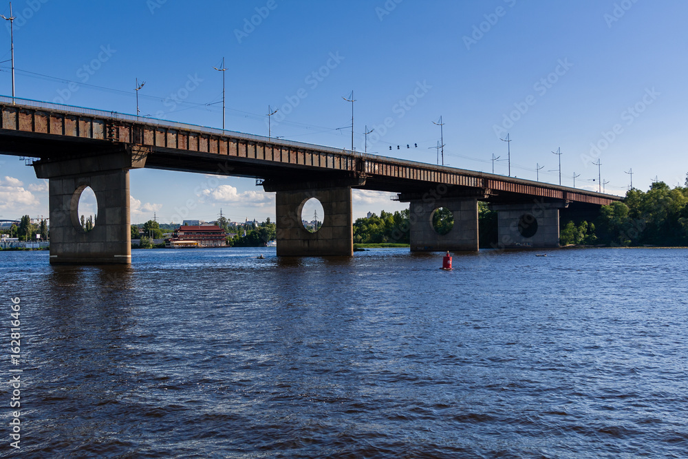 Bridge on a river against a blue sky and clouds