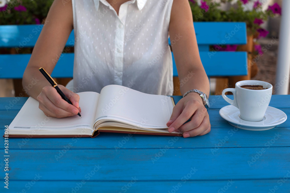 Obraz premium Young woman writing notes and drinking coffee