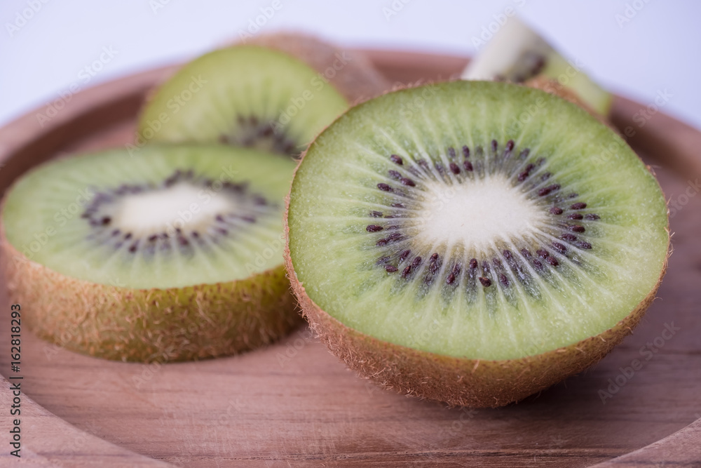 Whole kiwi fruit and sliced segments on wooden plate. Whole kiwi fruit and sliced segments on wooden plate.
