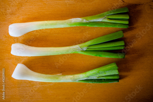 Three bunches of green onion on wooden table