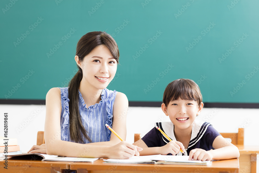 young Teacher helping child with writing lesson. young Teacher helping child with writing lesson.