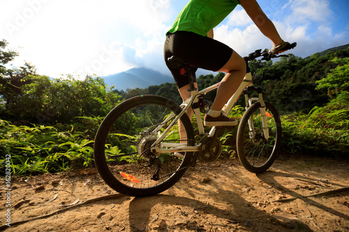 woman cyclist cycling on summer forest trail