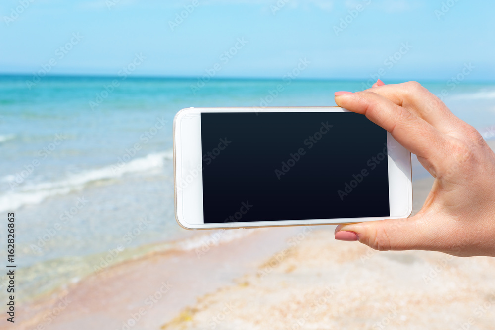 Beautiful woman's hand using smart phone at beach