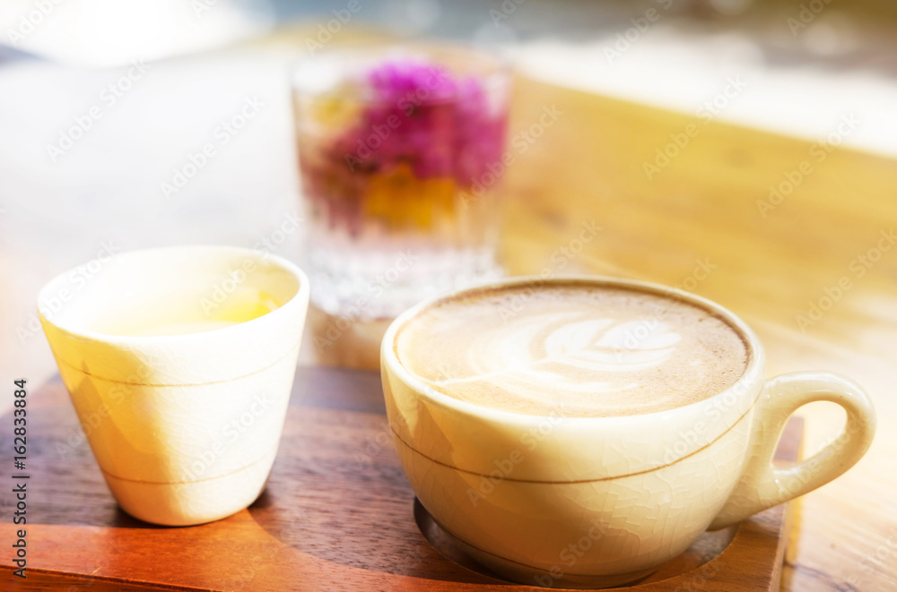 Cup of Latte art coffee and tea on wooden table with blurred effect Cup of Latte art coffee and tea on wooden table with blurred effect