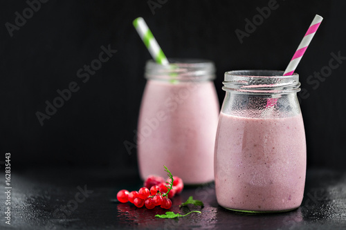 Two glasses with berry pink smoothies with currant and cranberry, selective focus photo