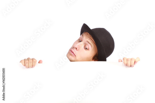 Young man hiding behind a billboard