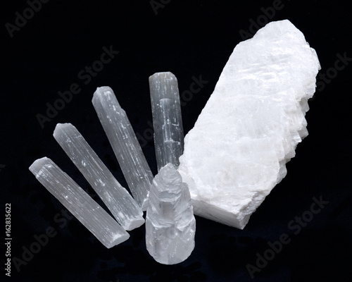 White mexican fish tail selenite with natural selenite rods on black background photo