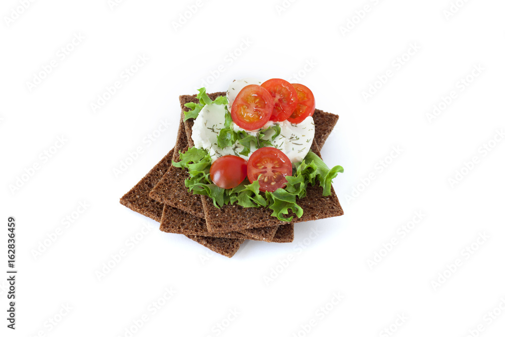 Healthy snack from wholegrain rye crispbreads crackers with Cherry tomatoes, salad and goat cheese