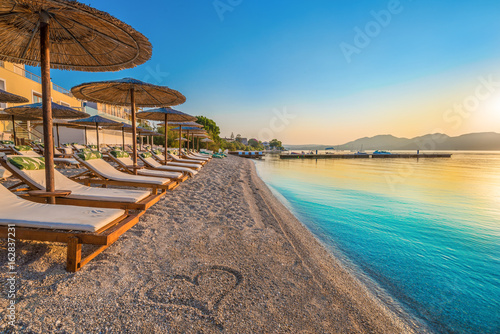 Fototapeta Naklejka Na Ścianę i Meble -  Beautiful view over Nikiana beach with chairs, umbrellas and a heart drawing on sand, in Lefkada island, Greece