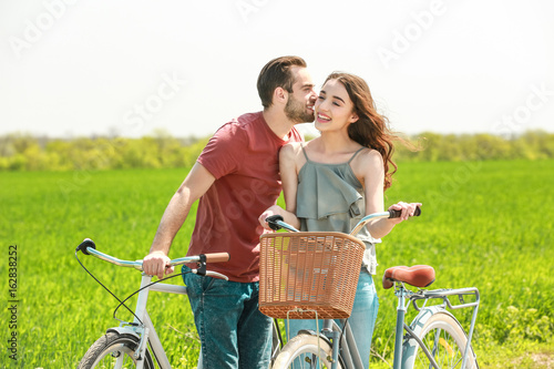 Happy young couple with bicycles in countryside