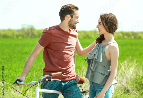 Happy young couple with bicycle in countryside