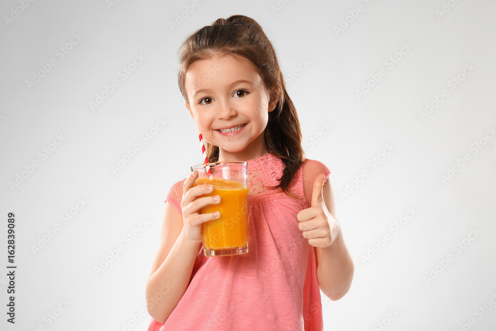 Cute little girl with glass of juice on light background Cute little girl with glass of juice on light background