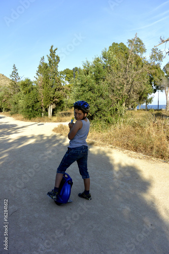El niño con el casco esta paseando en el parque con la rueda Monowheel..  scooter electrico photo