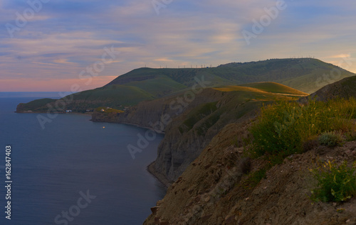 Scenic view of peaceful and calm green island with mountains and hills along coastline, ocean and clouds at sunrise. Panorama of amazing landscape by the sea with nobody around. Nature and environment