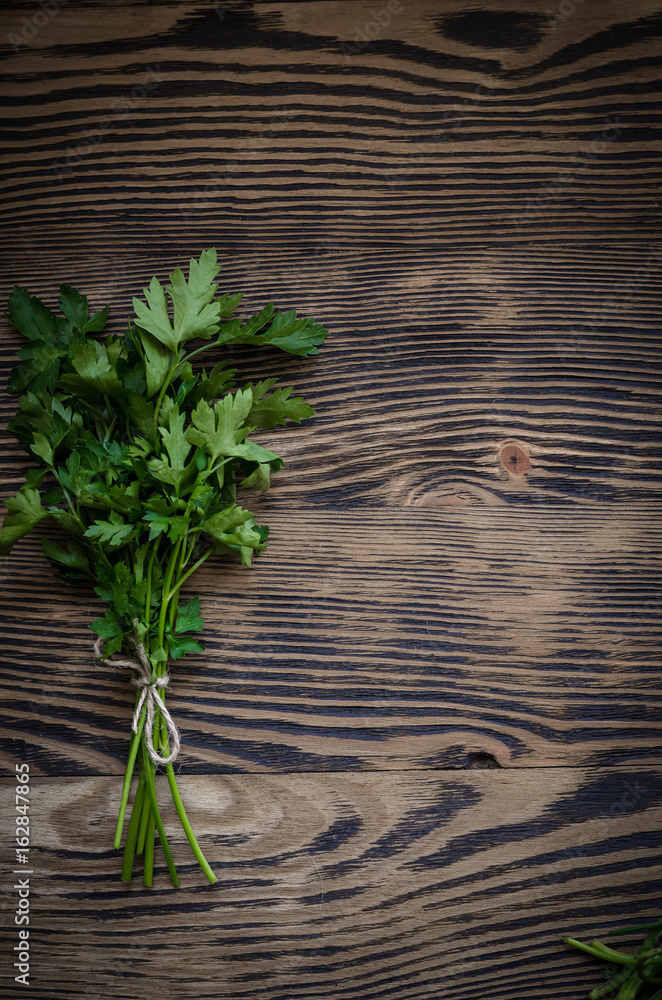 Obraz premium Fresh parsley on wood background.