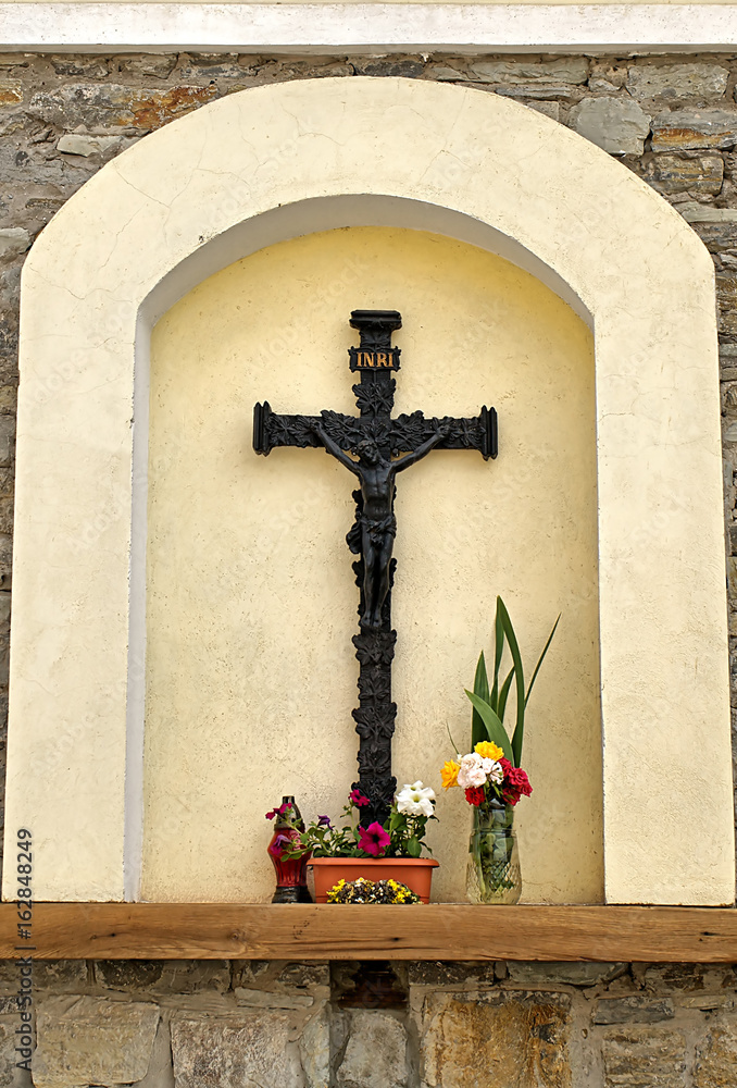 The arch with crucifix and flowers on the wall of an ancient church