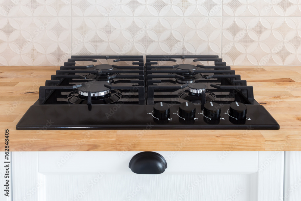 Build-in black gas hob on a wooden countertop in a traditional classic  kitchen with white facade foto de Stock | Adobe Stock