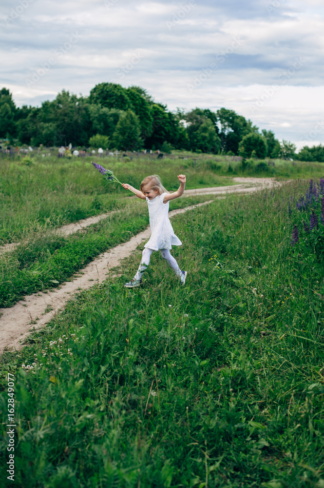 Child runs and jumps on a path in the field Child runs and jumps on a path in the field