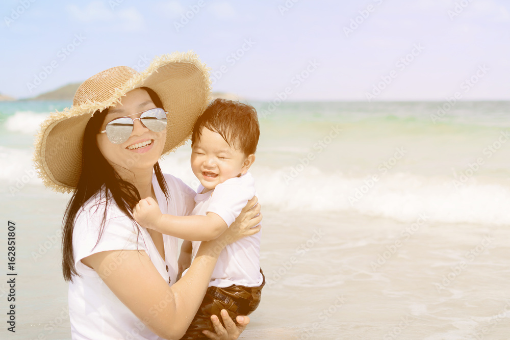 Happy family - mother and small baby son sit on beach Happy family - mother and small baby son sit on beach
