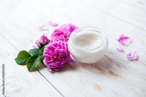 pot of moisturizing face cream and beautiful pink roses