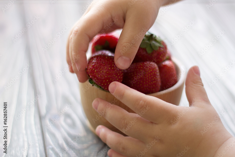 child's hands hold a bowl with strawberries child's hands hold a bowl with strawberries