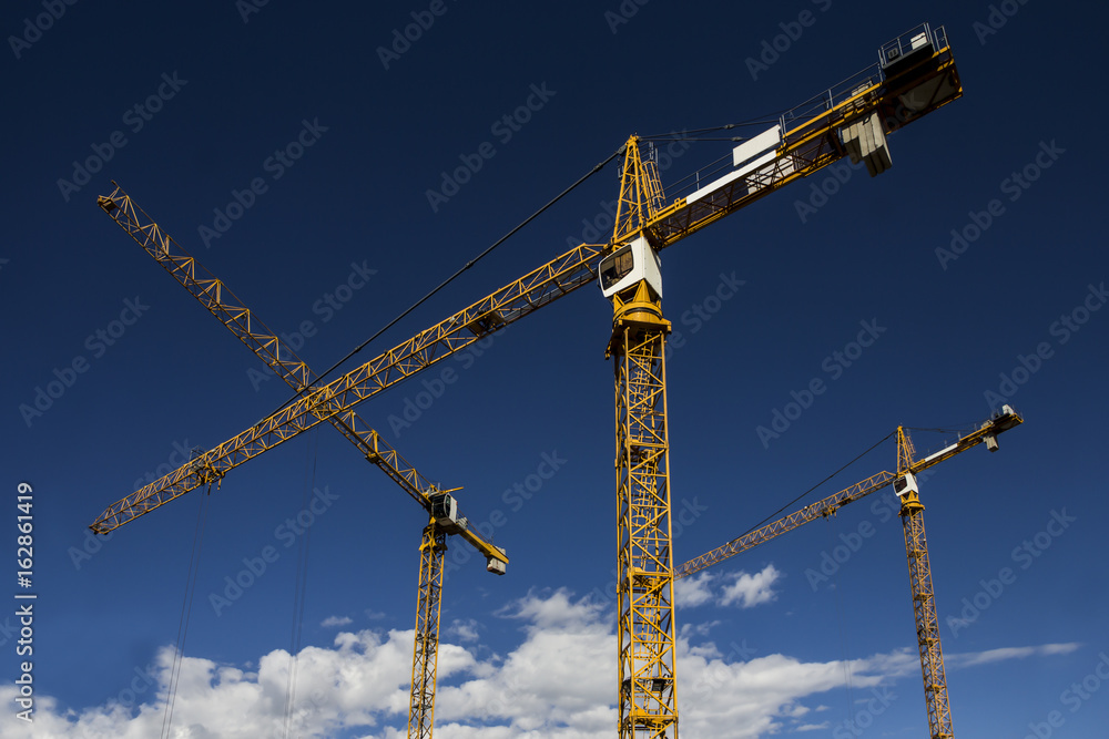 Some tower cranes on background of blue sky Some tower cranes on background of blue sky
