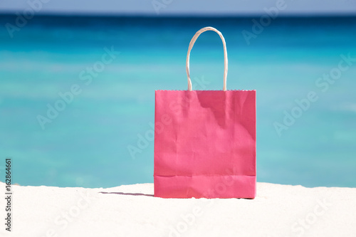 Shopping bag on sand against turquoise caribbean sea water