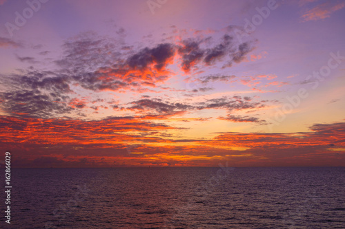 Fiery orange sunset sky warm light with clouds and sea, Beautiful for background