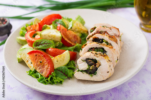 Baked chicken rolls with greens and olives, and baked vegetables - zucchini and tomatoes.