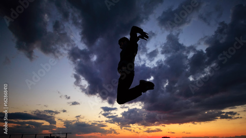 Silhouette of man on roof. Clouds and sunset