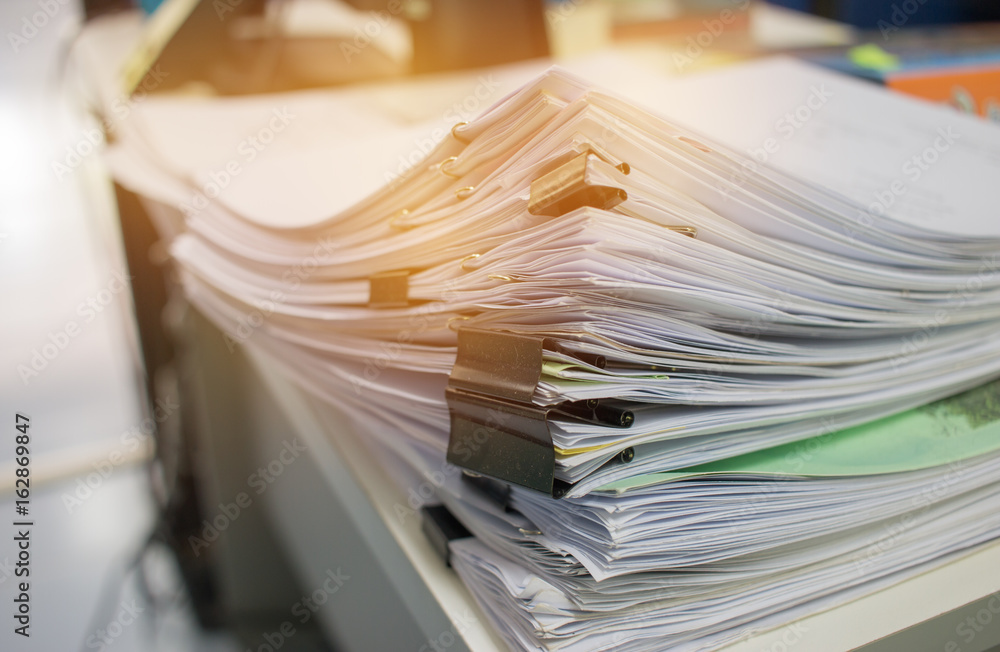 Stack of paper files on work desk in office Stack of paper files on work desk in office