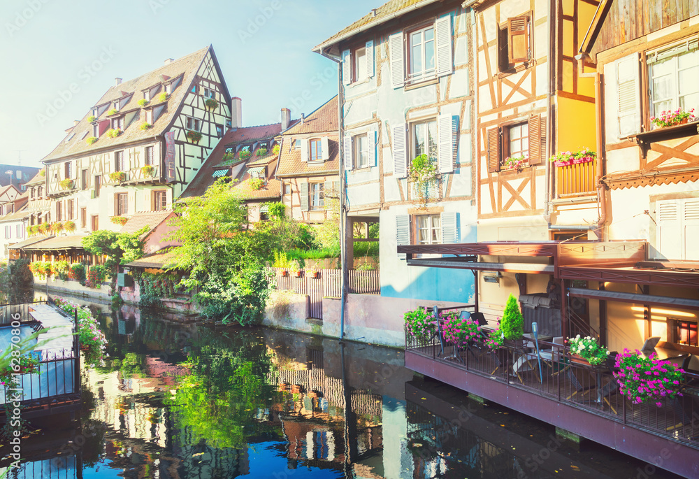 half timbered crooked houses of Colmar with reflections, Alsace, France, retro toned
