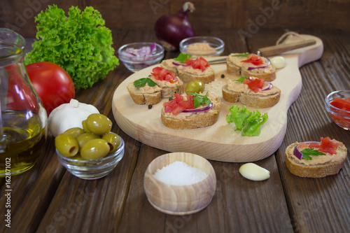 Sandwiches with tuna pate and various attachments on wooden board