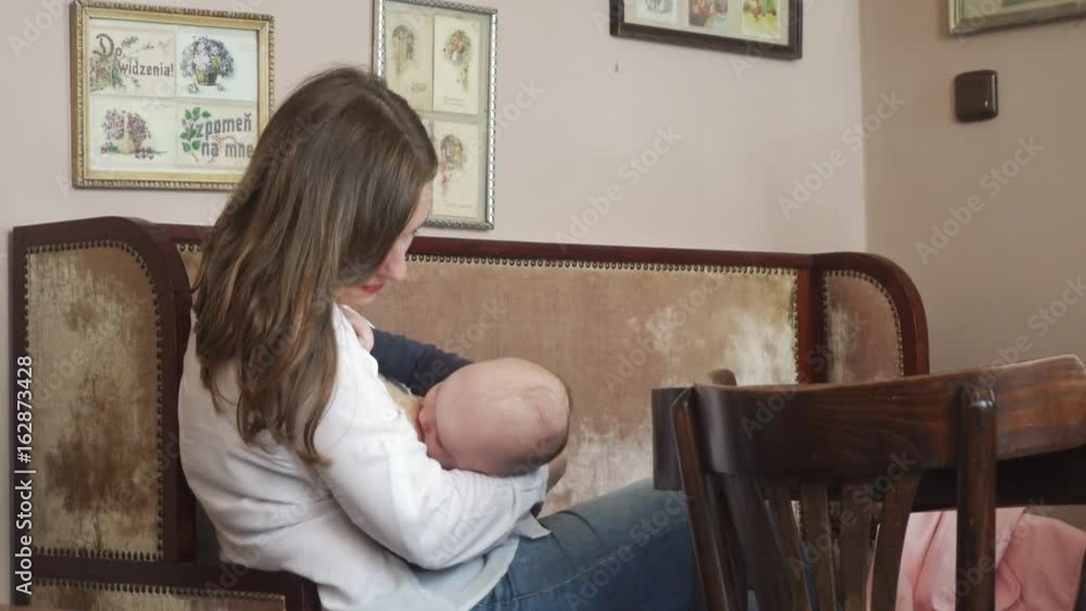A woman breastfeeding her child in a cafe. Medium shot A woman breastfeeding her child in a cafe. Medium shot