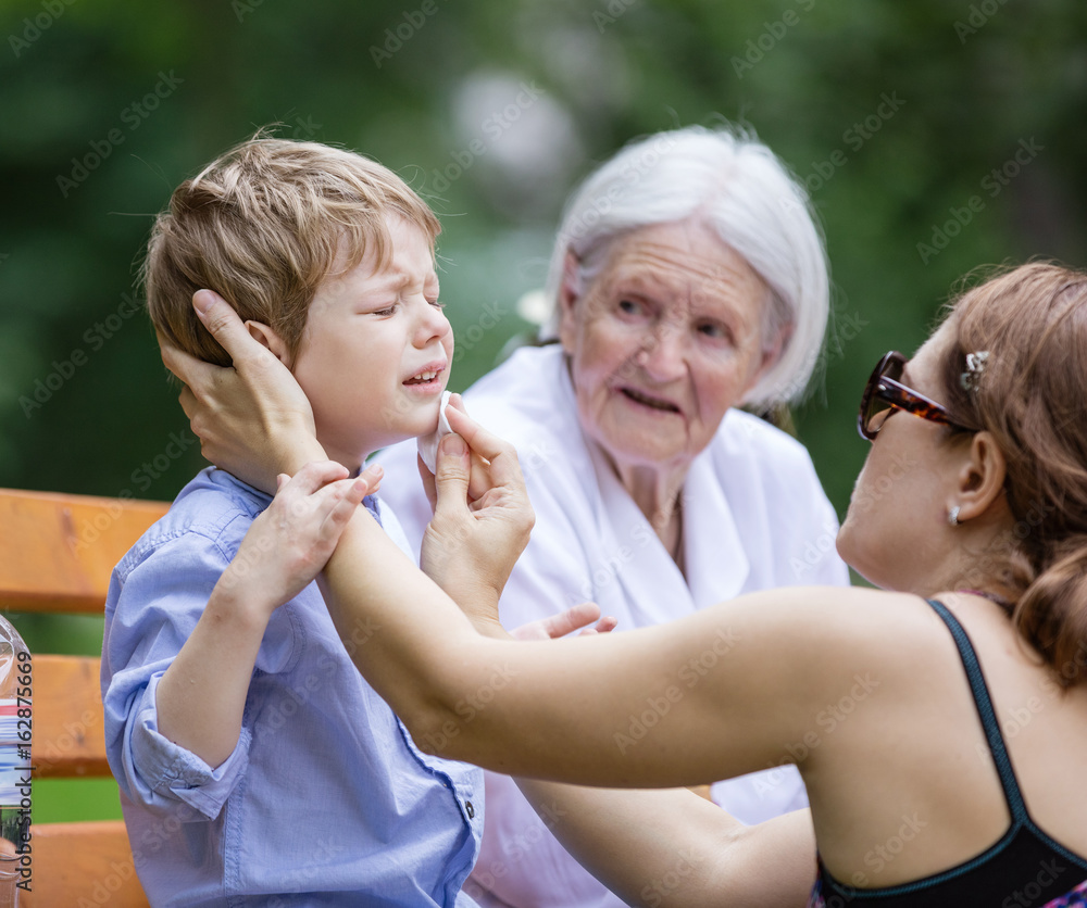Fototapeta premium Mother treating scrape on son's chin