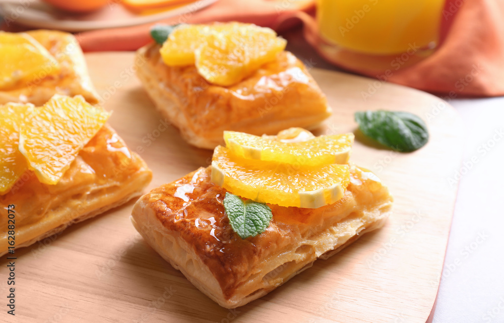 Tasty puff pastry dessert with orange and mint on wooden board Tasty puff pastry dessert with orange and mint on wooden board