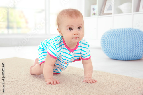 Cute little baby crawling on floor at home