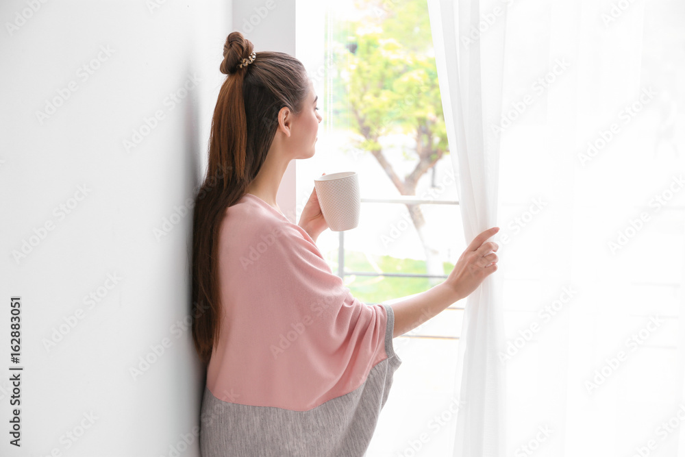 Beautiful woman drinking coffee and looking out window Beautiful woman drinking coffee and looking out window