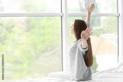 Free Download Young woman stretching after sleep against window - GFXLoad