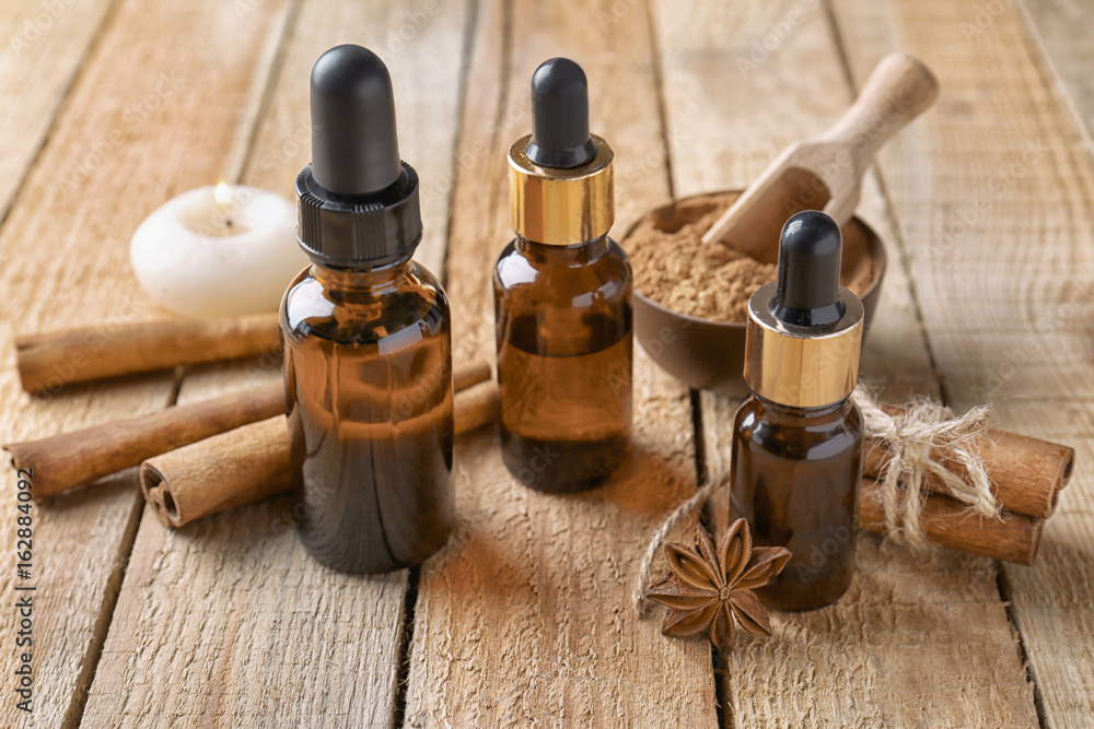 Composition with bottles of cinnamon oil on wooden background Composition with bottles of cinnamon oil on wooden background
