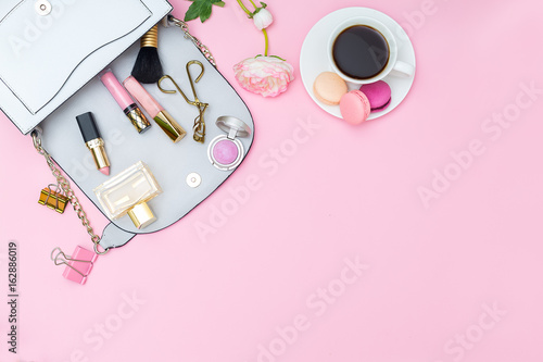 Women's handbag and accessories on a pink background. view from above