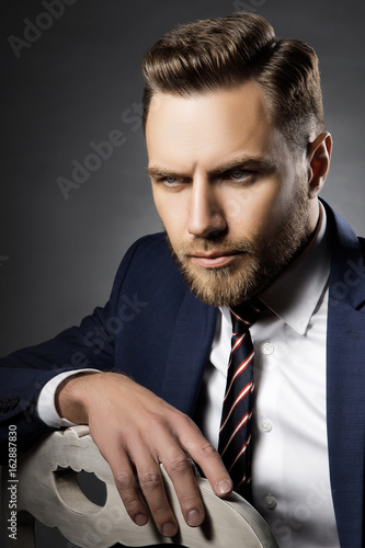 Handsome man with modern hair cut. Beard, suit and tie mens portrait photo