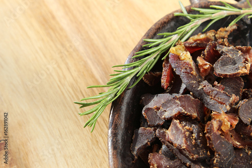 Biltong (dried meat) on a wooden board, this is a traditional food snack that can be found in South Africa. photo