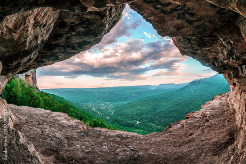 Beautiful scenic summer landscape view of Mezmay village from inside a weird rocky grotto in Caucasus mountains, Lenina Rock shelf, Russia