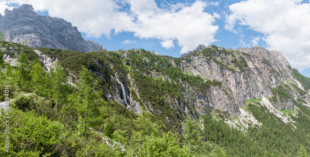 Fototapeta premium Waterfall at the foot of the mountain hut, Dolomites, Italy